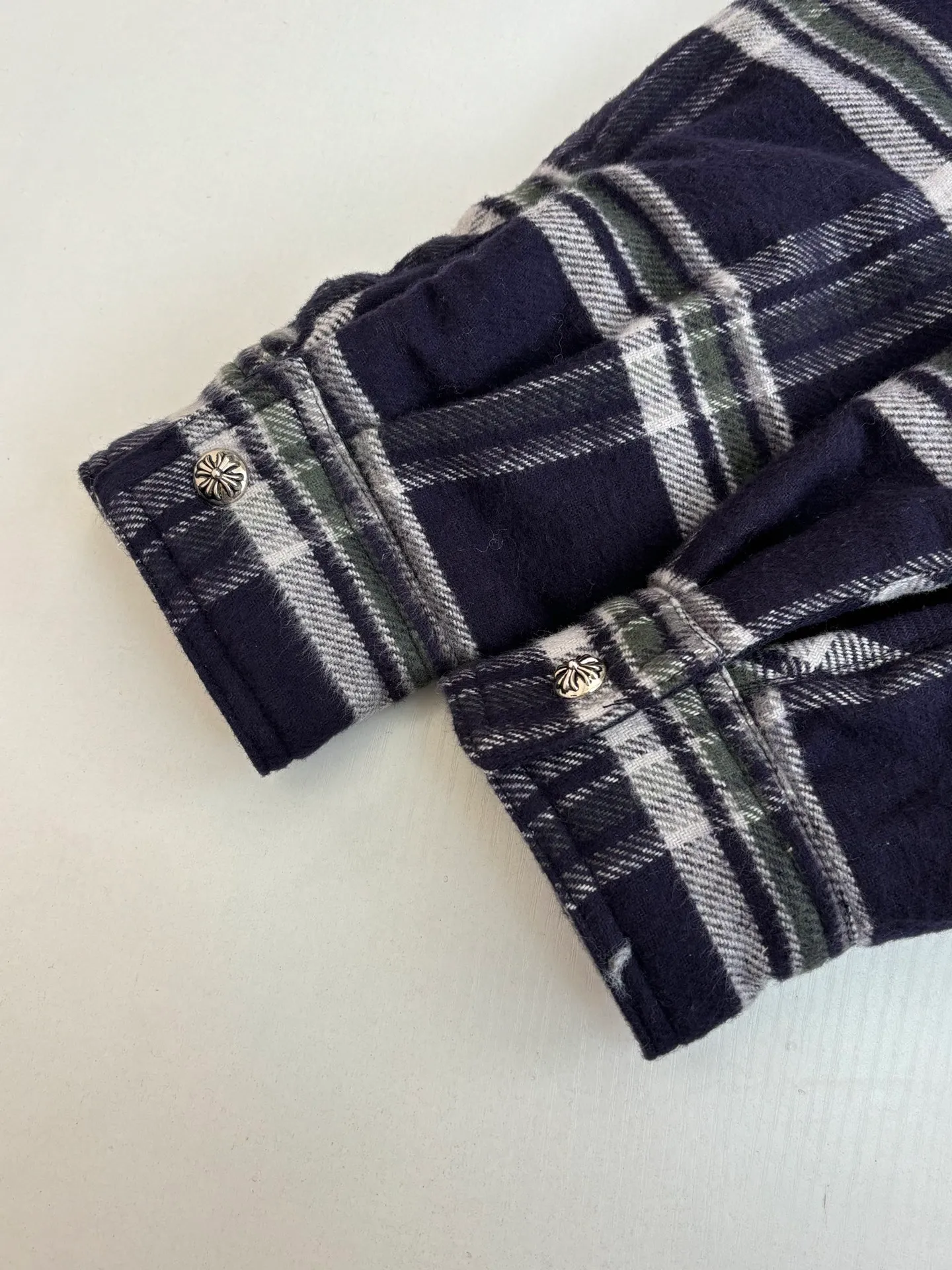 P670 Chrome Heart*/Chrome Heart Contrast Plaid Lapel Shirt Jacket. The fabric is made of 100% cotton fabric to create a navy blue main tone plaid. The rough plaid lines blend into the brand's iconic Gothic rebellious gene. The stiff cotton material supports the street silhouette, and the plush fabric inside adds softness and warmth. The collision of cold silver hardware and soft and warm inner wear is the dark aesthetic of Chrome Hearts' "symbiosis of hard core and gentleness". The autumn and winter layering has its own rock and roll accent.  Size：S/M/L/XL